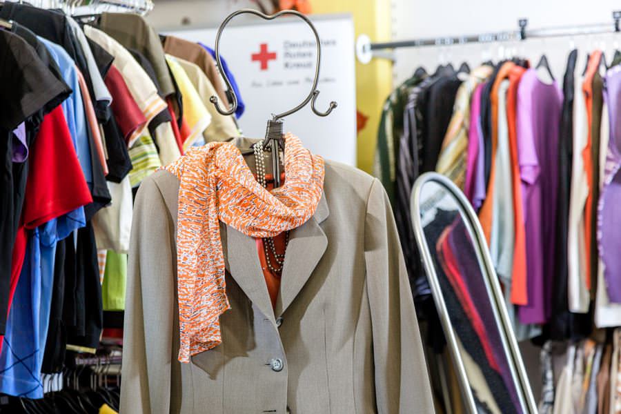 Die Kleiderkammer ist mit gespendeter Kleidung gefüllt, darunter Jacken, Pullover und andere Textilien, die in Regalen sortiert sind. Diese Einrichtung unterstützt bedürftige Menschen, indem sie gut erhaltene Second-Hand-Kleidung kostenlos oder für einen symbolischen Betrag bereitstellt.