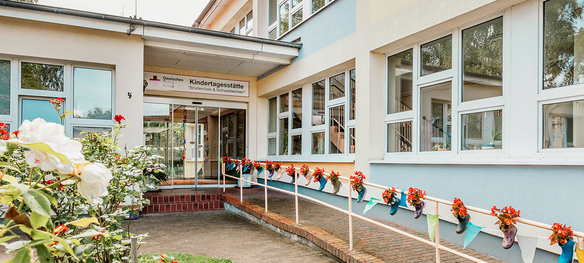 Bunte Gummistiefelblumentöpfe schmücken den Eingangsbereich der DRK-Kindertageseinrichtung Brüderchen und Schwesterchen, Kita Bergen Süd.
