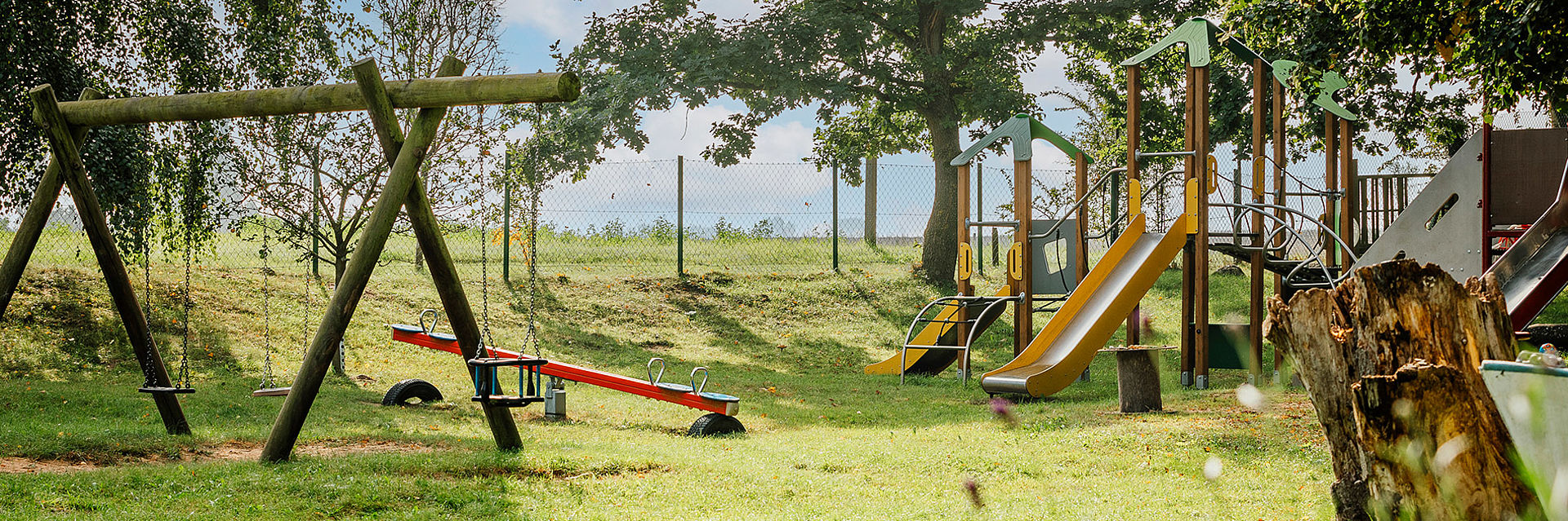 Im Außenbereich der DRK-Kindertageseinrichtung "Hasenbande" in Dreschvitz bieten verschiedene Spielgeräte, wie Schaukeln, eine Wippe sowie ein Klettergerüst mit Rutsche abwechslungsreiche Bewegungsangebote für die Kinder.