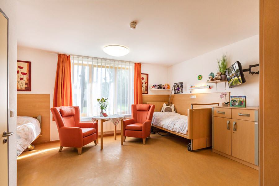 DRK-Pflegeeinrichtung Glowe, Doppelzimmer mit Pflegebetten, gemütlichen Sesseln, großes Fenster un viel Licht, Fernseher, persönlichen Dekoration, Menschen mit Behinderungen