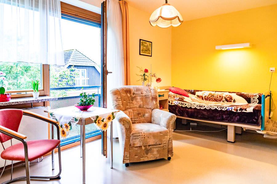 DRK-Pflegeeinrichtung Gingst, Zimmer mit großem Fenster und viel Licht , Sessel, Pflegebett