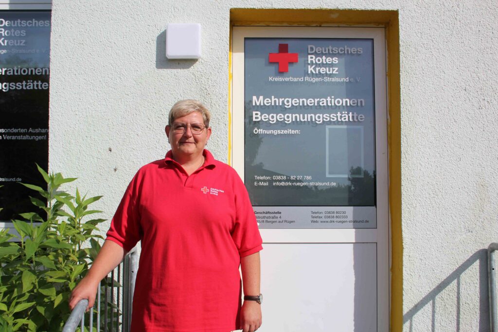 Mitarbeiterin des DRK steht vor der Mehrgenerationen-Begegnungsstätte in Bergen-Süd, die Menschen aller Altersgruppen einen Ort für Austausch und Unterstützung bietet.