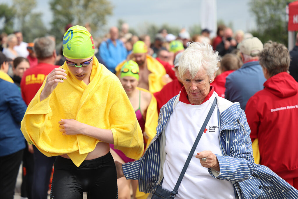 Ein Mitglied des DRK-Ortsvereins Poseritz legt einem Schwimmer nach dem Vilm-Schwimmen ein Handtuch über die Schultern.